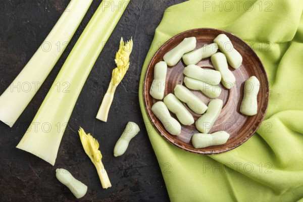 Jelly celery candies on black concrete background and green linen textile. close up, top view, flat