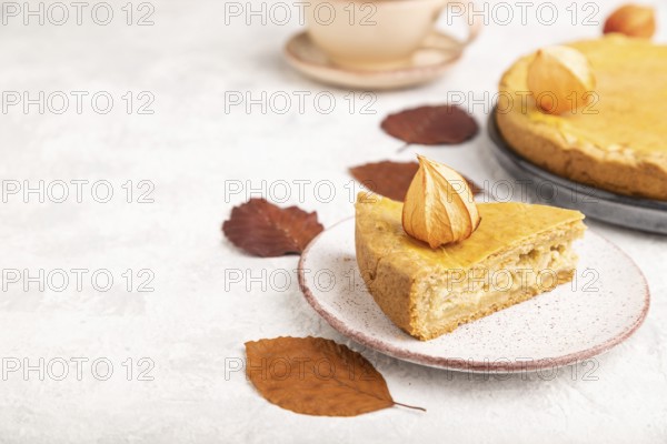 Autumn onion pie decorated with leaves and cup of coffee on gray concrete background. Side view,