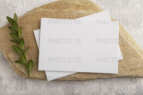 White paper business card, mockup with natural stone and boxwood branch on gray concrete background