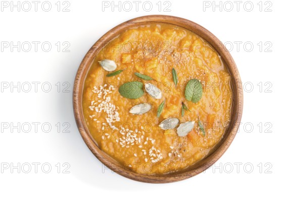 Sweet potato or batata cream soup with sesame seeds in a wooden bowl isolated on a white background