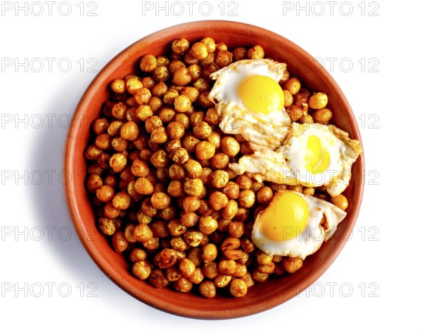 Fried chickpeas with quail eggs and spices in a clay plate isolated on white background, top view
