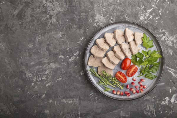 Boiled pork tongue with tomatoes and herbs on a black concrete background. Top view, copy space,