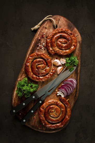 Fried spiral sausages, on a wooden board, top view, with spices, no people
