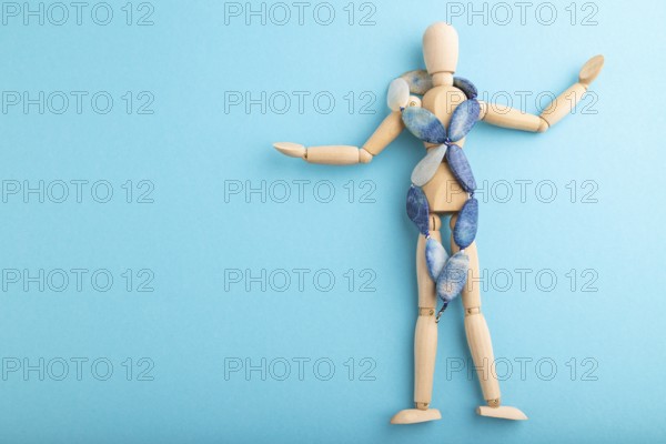 Wooden mannequin with blue agate beads on blue pastel background. copy space, isolated, luxury, bad