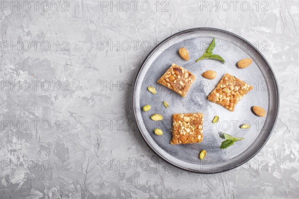 Traditional arabic sweets in gray ceramic plate on a gray concrete background. top view, copy space