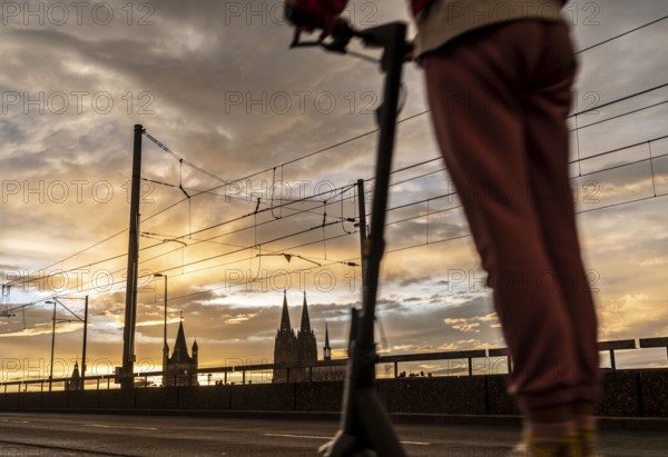 Skyline with Cologne Cathedral, Gross St. Martin Catholic Church, Deutz Bridge, sunset, e-scooter
