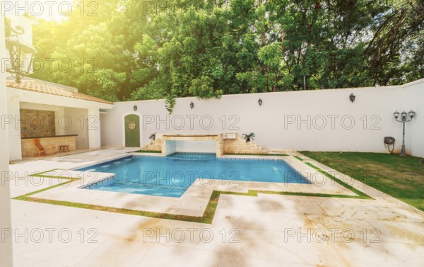 Homemade swimming pool surrounded by nature trees. Beautiful crystal clear swimming pool in a