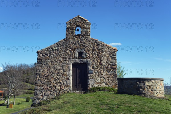 Historische Kirche aus Stein mit kleinem Glockenturm, umgeben von Gras und einem klaren blauen
