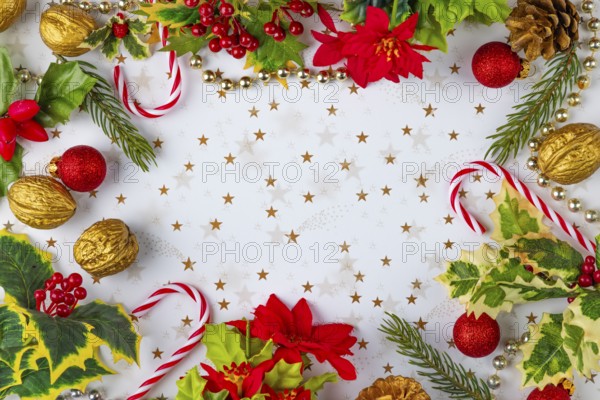 Frame made of Christmas decorations, such as fir branches, baubles, nuts, candy canes on a white