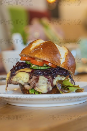 Burger with melted cheese and vegetables on a pretzel bun, autumn creations, Cafe Kuh,