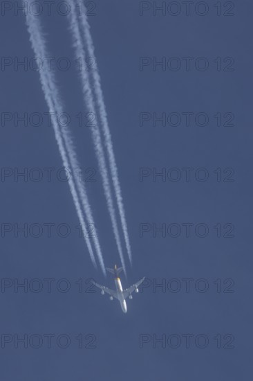 Boeing 747 jumbo jet cargo aircraft of UPS flying in a blue sky with a vapor trail or contrail