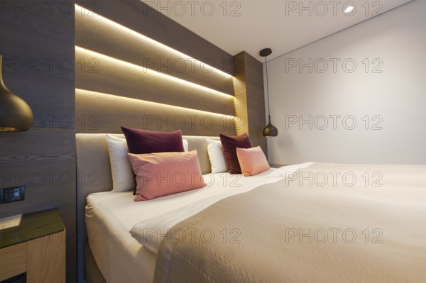 Modern bedroom with large bed, backlit wall and cosy atmosphere, Mayrhofen, Zillertal, Austria,