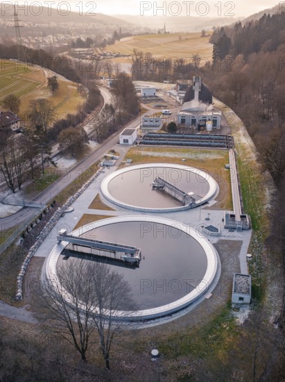 Aerial view of a sewage treatment plant focussing on the round clarifiers next to a forest, Nagold,