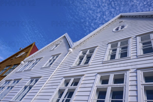Traditional wooden houses under a blue sky with pitched roofs and multiple windows in a sunny old