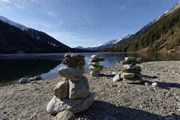 Cairns in winter on the icy lake, Lake Antholz in the Antholz Valley, Val Pusteria, South Tyrol,