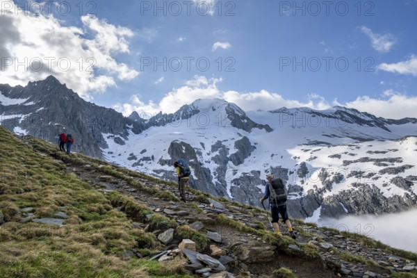 Mountaineers on a hiking trail, high fog in the valley, glaciated mountains with Furtschagelkees,