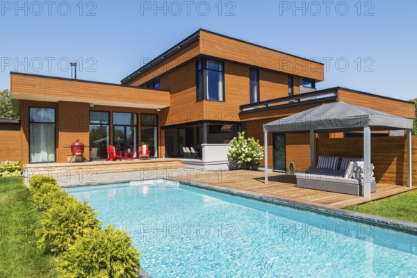 Rear of modern cube style home with stained horizontal wood cladding, in-ground swimming pool and