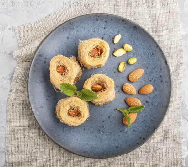 Kunafa, traditional arabic sweets in blue ceramic plate on a gray concrete background. top view,