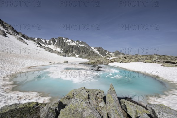 Frozen meltwater lake with snow-covered mountains in the background, Neukirchen am Großvenediger,