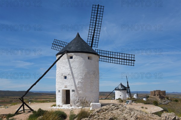 Several white windmills under a clear sky in a wide, sunny landscape, Consuegra, Toledo,