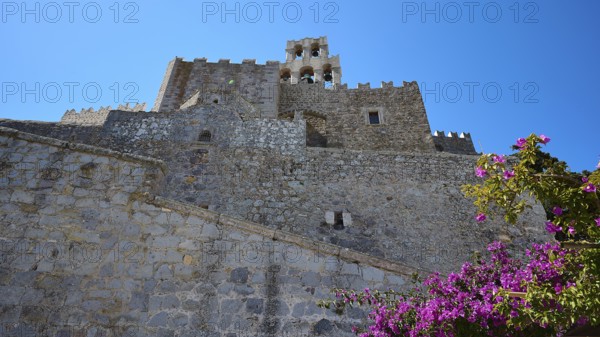 Historic castle walls with blooming flowers and clear blue sky, Agiou Theologou Monastery, St