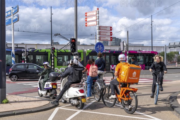 Cyclist, moped rider, waiting at a red traffic light, Feijenoord, in front of the Erasmus Bridge,