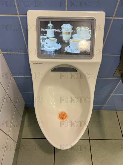 Toilet in a service station, on a motorway, gents, urinal with built-in video monitor, shows