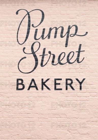 Close up sign on pink painted brick wall, Pump Street Bakery, Orford, Suffolk, England, UK