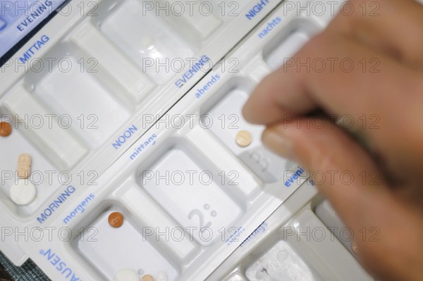 Symbolic photo on the subject of taking medication in old age. Two senior citizens sort various