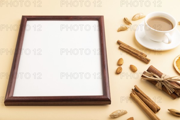 Composition with wooden frame, almonds, cinnamon and cup of coffee. mockup on orange background.