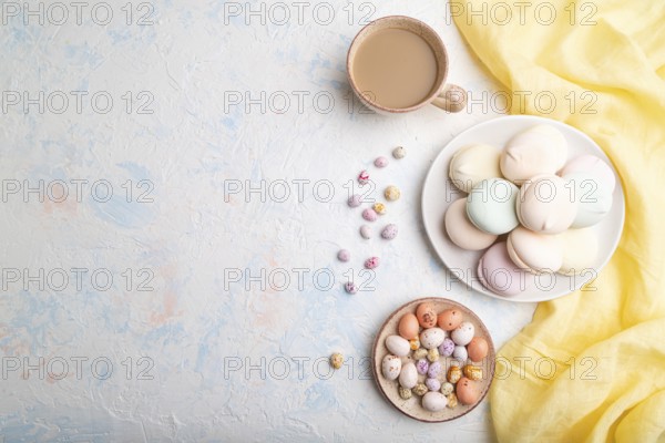 Colored zephyr or marshmallow with cup of coffee and dragees on white concrete background and