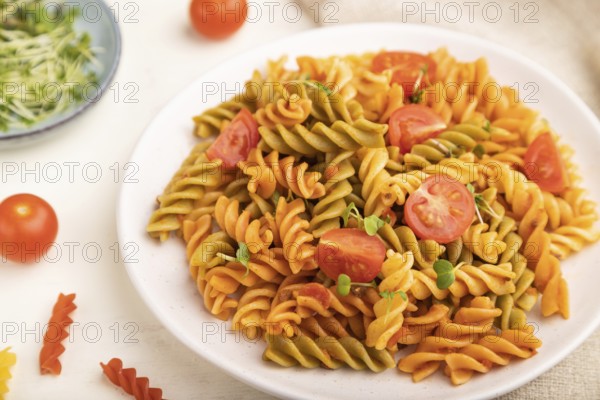 Tortiglioni semolina pasta with tomato and microgreen sprouts on a white wooden background and