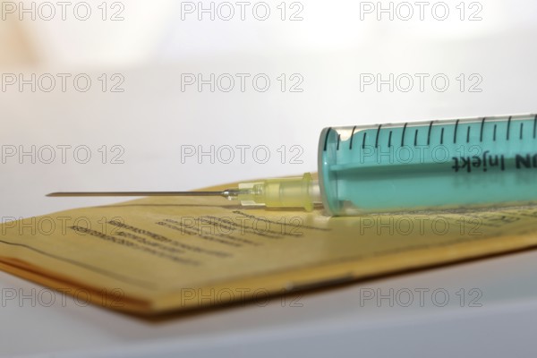 Symbolic image of vaccine with vaccination card and syringe