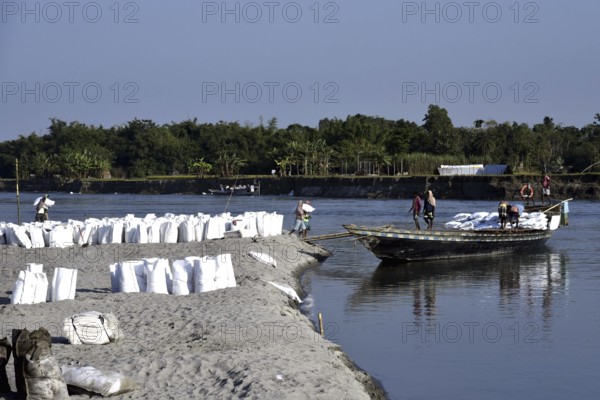 Public Works Department (PWD) of Assam labourer carrying sand bag to boat in Beki River to make