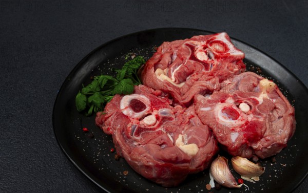 Raw steak, calf's neck on the bone, fresh meat, on a black plate, top view, no people