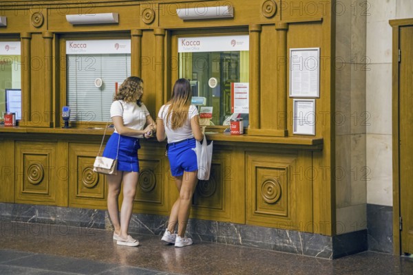 Two young Russian girls buying metro tickets at the ticket office, pay desk, box office of the