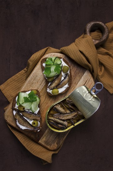 Sandwiches, black bread with sprats, cream cheese, cucumbers, on a cutting board, top view,