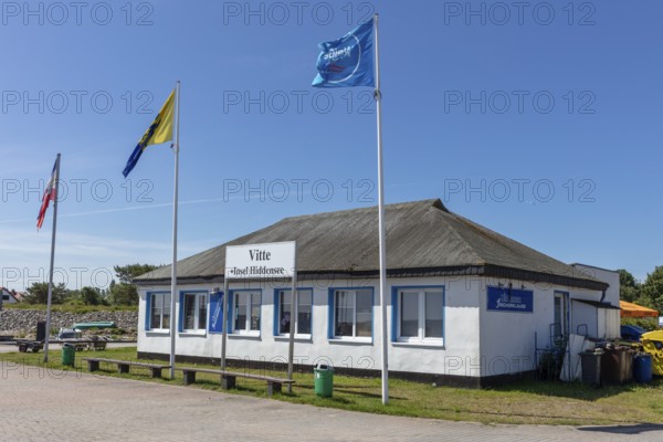 Small historic building with waving flags under a blue sky in sunny weather, Rügen, Hiddensee
