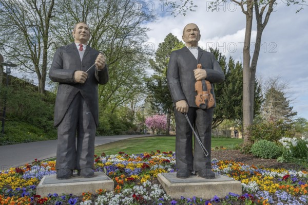 Statues of two men, one with a violin, the other with a conductor's baton, stand in a colourful