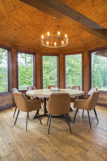 Round wooden dining table with tan leather armchairs in dining room inside a milled Eastern white