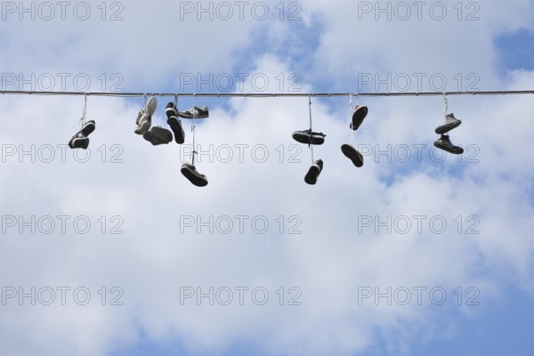 Shoes hanging on a wire against a blue sky with scattered clouds, Bad Mergentheim,