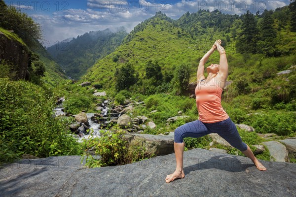 Yoga outdoors, woman doing Ashtanga Vinyasa Yoga asana Virabhadrasana 1 Warrior pose posture at