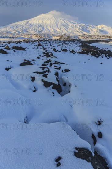 Lava field in front of a volcano, evening light, sun, snow, winter, Arnarstapi, Snaefellsjökull,