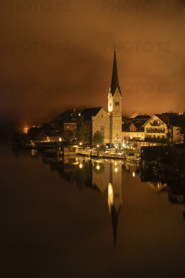View of Hallstatt with the church and Lake Hallstatt at night. Clouds move through Hallstatt.