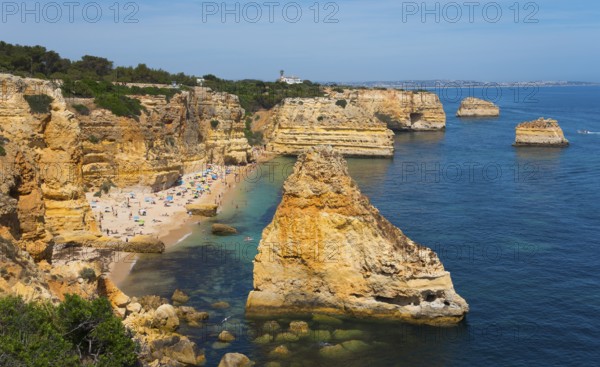 Coastal landscape with rocky cliffs and a beach on the clear blue ocean under a sunny sky, Praia da