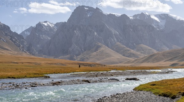 Mountain landscape with yellow meadows, Kol Suu River and mountain peaks with glaciers, Keltan