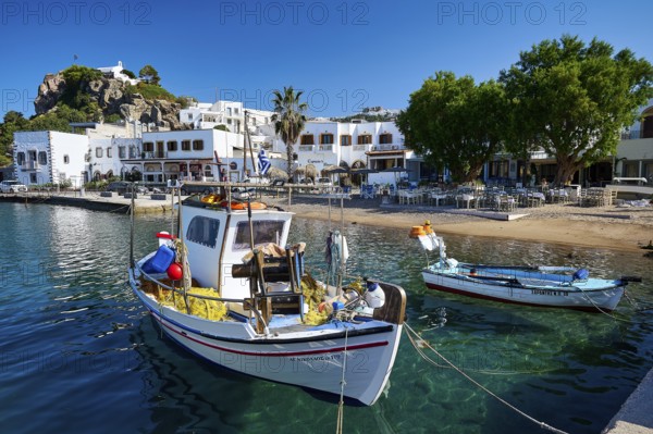 Two fishing boats moored at a harbour quay on a Greek island, surrounded by clear water and