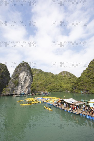 Holidaymakers queue for a kayak on a jetty, behind the karst rocks in Lan Ha Bay, Halong Bay,