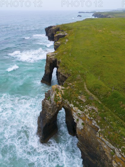 Steep coastline with characteristic rock arches and thundering waves crashing against the rocks,