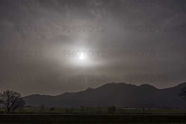Sahara dust covers the sun in front of a mountain landscape, spring, Loisach-Lake Kochel-Moore,